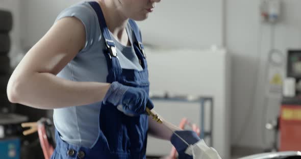 Professional female mechanic checking a car's engine oil using a dipstick