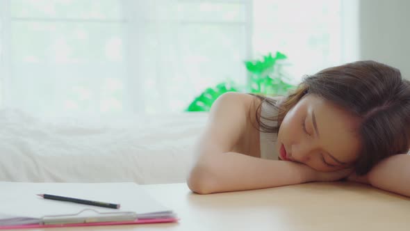 Over work Asian young woman sleep on work table in bedroom alt