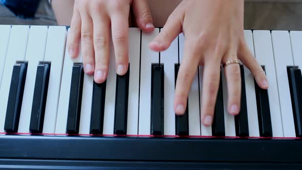 Young woman playing electronic piano at home alt