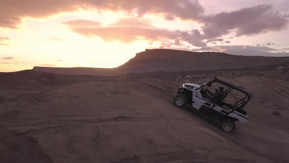 Aerial panning view of OHV driving over dirt hill in the desert alt