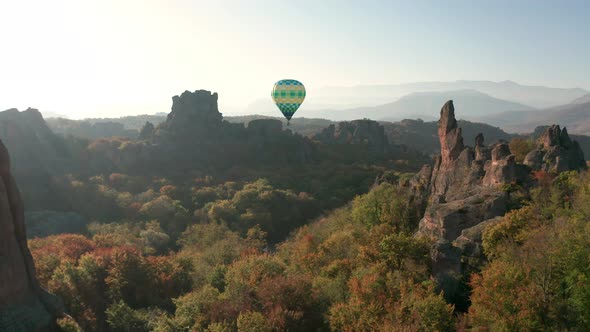 Hot air balloon flying over picturesque rock formation alt