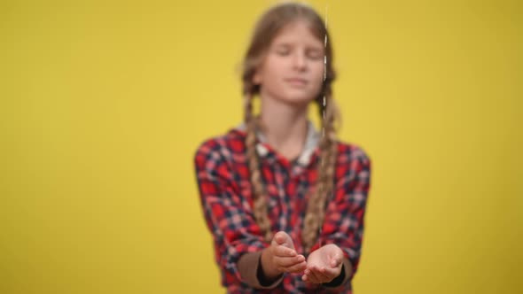 Water Pouring in Slow Motion on Hands of Blurred Teenage Caucasian Girl at Yellow Background alt