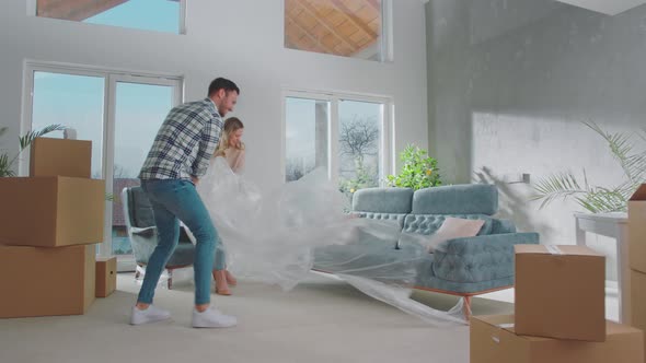 Couple removing cover from sofa alt