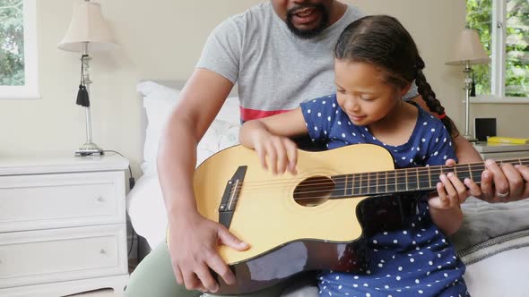 Father and daughter playing guitar in bedroom 4k alt