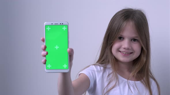 Cute Child Girl Shows Phone with Green Screen Mock Up Cellphone Mobile Telephone alt