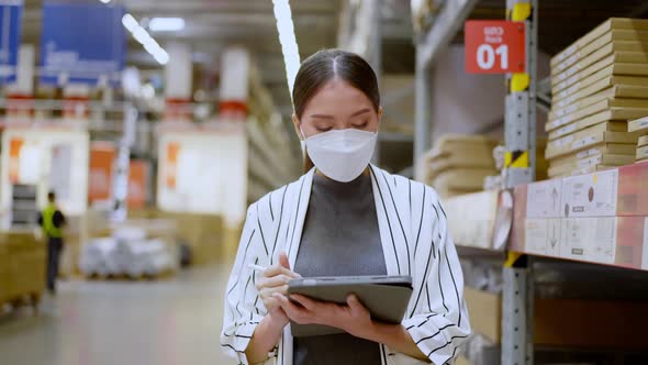 Asian woman business owner wear face mask using digital tablet checking stock
