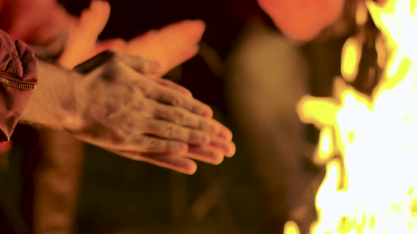 Close Up of Man Warming Up His Hands at Camp Fire alt
