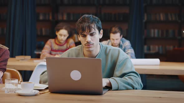 Young Man Student Prepare for Examinations at Library Using Laptop alt
