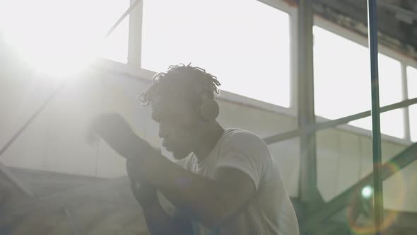 Male Boxer Practicing Shadow Boxing Around the Metal Structures Indoors Lens Flares alt