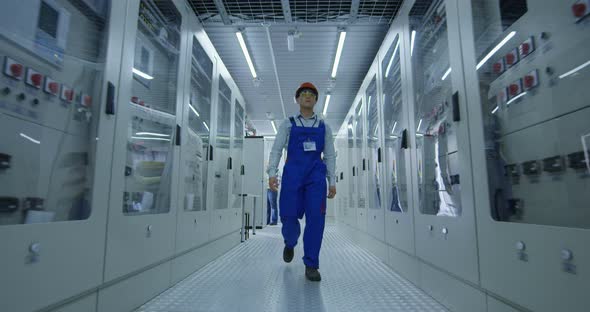 Asian Worker Walking in Hallway of Power Station alt