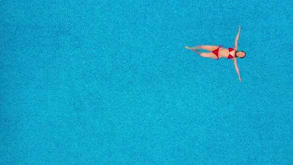 View From the Top As a Woman in a Red Swimsuit Lying on Her Back in the Pool. Relaxing Concept alt
