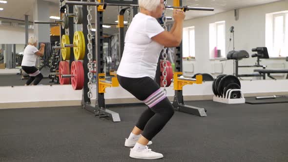 Elderly Woman Gray Hair Plays Sports in Gym alt