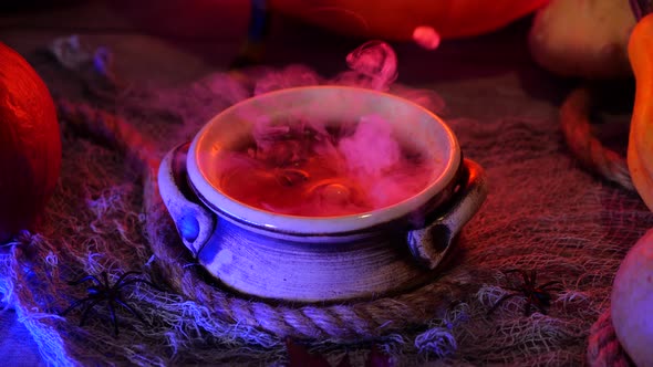 Halloween party decoration on a spooky background. Smoky bubbling witch cauldron with poison