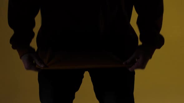 A Man in a Yellow Jacket Adjusts His Clothes Against a Background of Studio Color alt