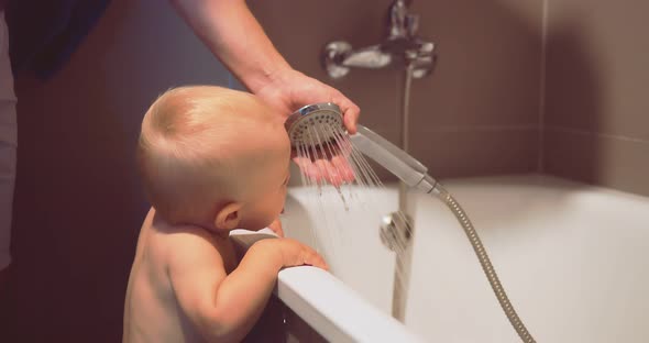 Naked Kid in the Bathroom Looks at the Water From the Shower and Tries to Lick It alt