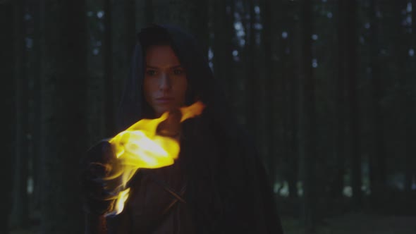 Woman walking in the forest with a fire torch alt