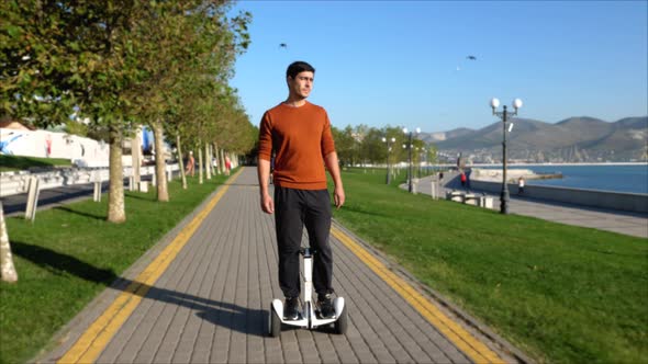 A Man is Riding Segway at the City on Seafront Front View