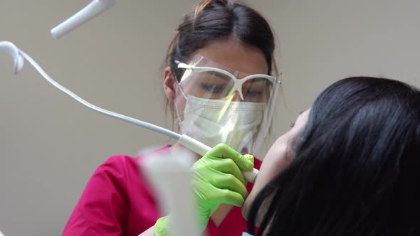 Woman at the Dental Hygienist Getting Professional Tooth Whitening and Ultrasound Cleaning alt