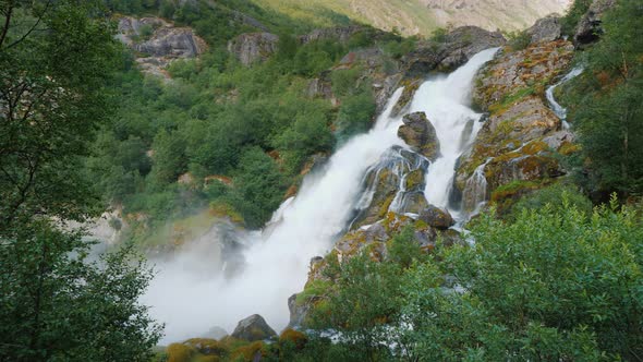 The Majestic Nature of Norway Is a Waterfall From the Meltwater of the Briksdal Glacier alt