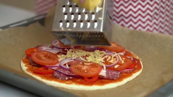 Woman Chef Puts Grated Cheese on Pizza