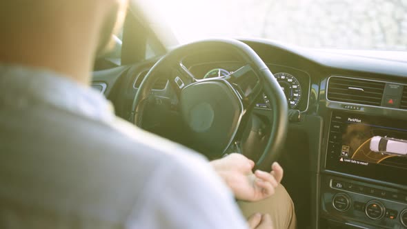 Person's Hands Holding Steering Wheel While Driving Modern Electric Car on the Street Road