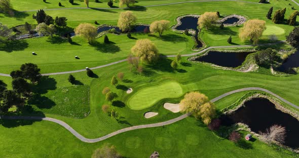 Top down aerial shot of golf carts driving through a green and lush golf course. alt