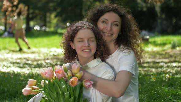 Portrait of a Woman Hugging Her Teenage Daughter with a Bouquet of Tulips