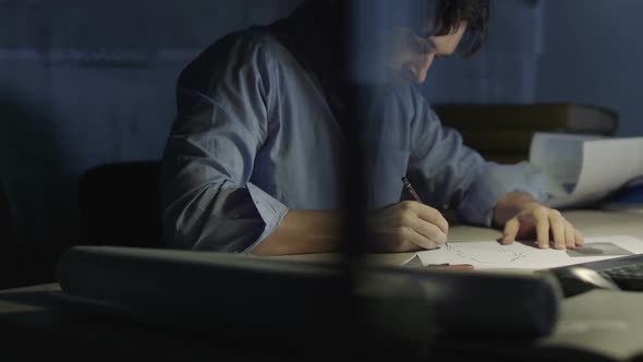 Young Man Artist Draws A Sketch In The Office at Night
