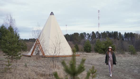 Young Beautiful Woman Walking Through Countryside to Glamping Outside Teepee