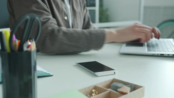 Close-up Shot of Man's Hands Typing with Laptop Computer Then Using Smarphone alt
