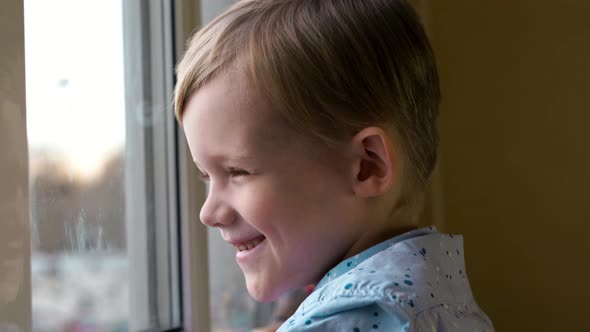 Happy Of Smiling Little Boy is Looking On Window alt