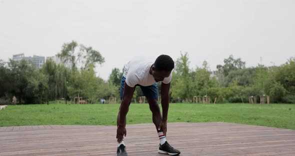 African American Man Warming Up with Exercises Before Intense Workout Outdoors alt