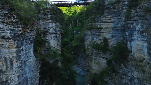 Aerial zoom-in shot of a metal bridge in the Osum canyon in Albania. High rocky cliffs and natural r alt