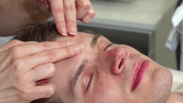 Cropped Shot of a Professional Masseuse Massaging Forehed of Male Client alt