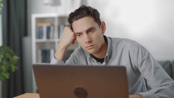 Focused Man Working on Laptop at Table alt