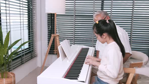 The family's grandfather was happy to listen to her granddaughter play the piano and clapped her han alt