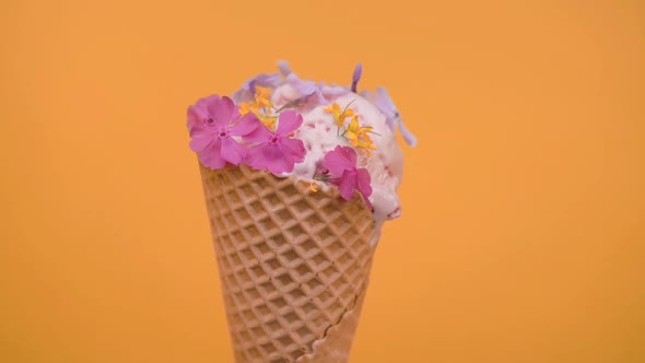 Ice cream scoop in waffle cone decorated with spring flowers, vanilla style