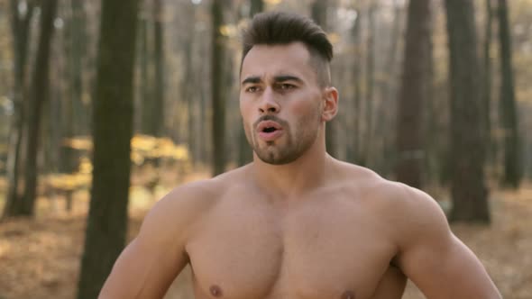 Young Athletic Guy With Naked Torso Stands In The Woods And Does Breathing Exercises. alt