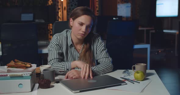 Tired Female Office Worker Closing Down Her Laptop and Banging Head on Arms. Stressed Businesswoman alt