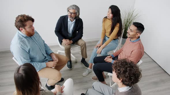High Angle View of People Citting in Circle Talking and Gesturing During Group Therapy alt