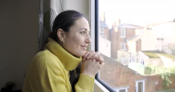 Woman at home looking out of the window and enjoying the view, planning futur