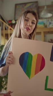 Two Attractive Young Girls are Standing in the Studio with Lgbt Posters in Their Hands and Looking alt