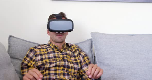 Young man using virtual reality headset in living room at home 