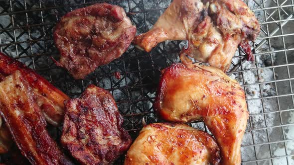 Assorted delicious grilled meat over the coals on a barbecue, top view and zoom out.