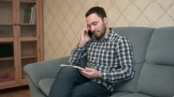 Man Talking on the Phone While Using Tablet alt