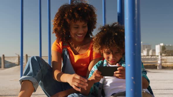 Mother and son using phone at playground alt