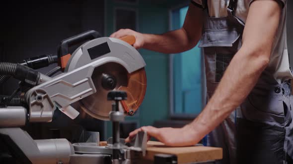A Builder Cuts a Wooden Board on a Table Circular Saw in Construction Studio alt