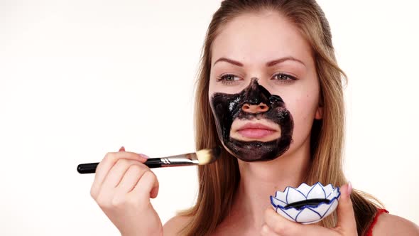 Girl Applying Black Mask to Face alt