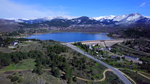 Panoramic aerial view over the Navacerrada Reservoir with the beautiful snow-capped mountains on the alt