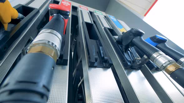 Person's Hand Puts a Green-handled Petrol Nozzle Back Into the Pump alt
